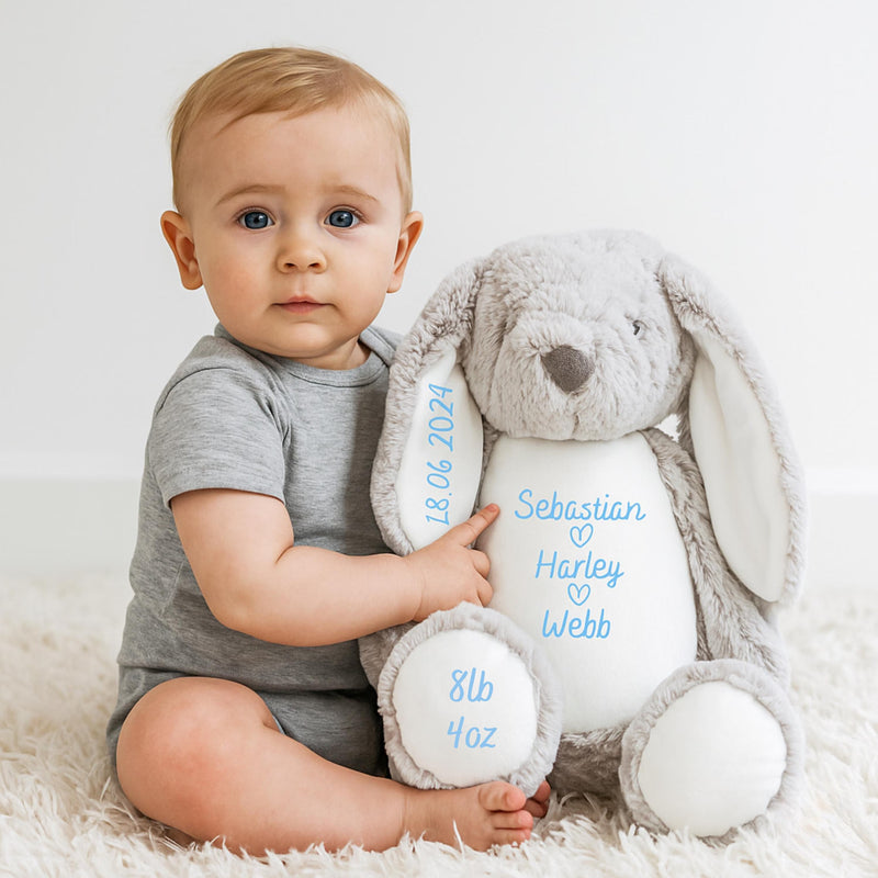 baby holding a teddy with personalised name and date on ear and foot
